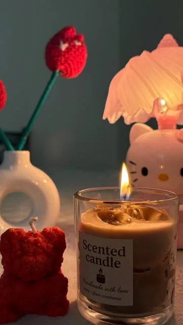 Red crochet tulips beside a scented candle and a kitty lamp